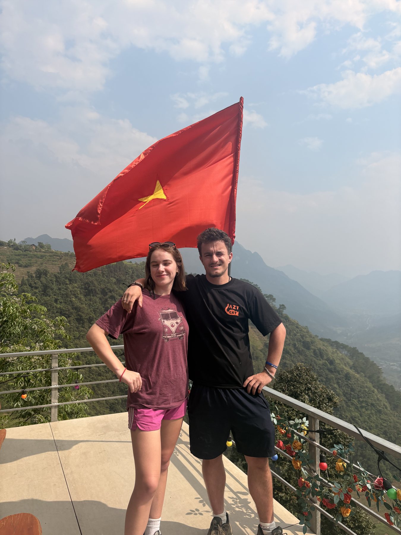 Ollie and a fellow traveller standing beneath the Vietnamese flag in the Ha Giang mountains